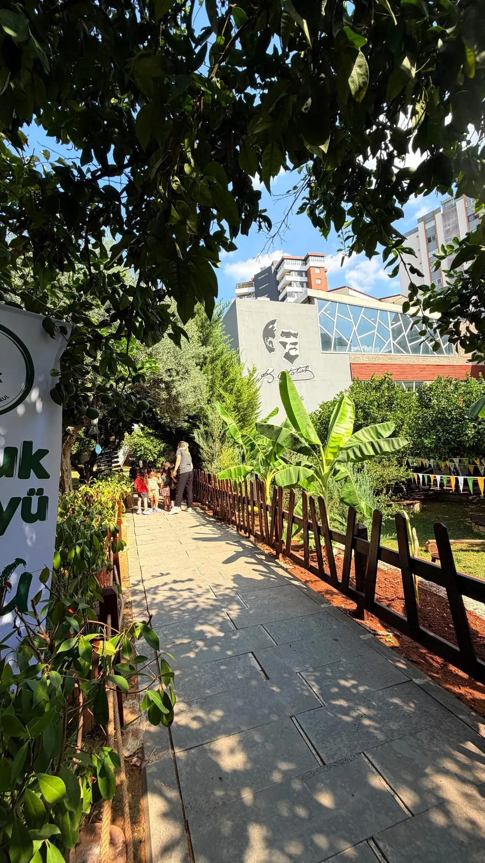 Ağaçların gölgelediği taş yürüyüş yolu ve ahşap çitler